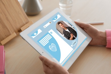 Young woman visiting online dating site via tablet at table, closeup