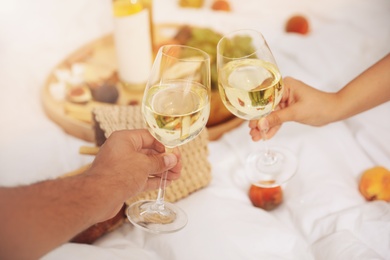Photo of Couple with wine imitating picnic at home, closeup
