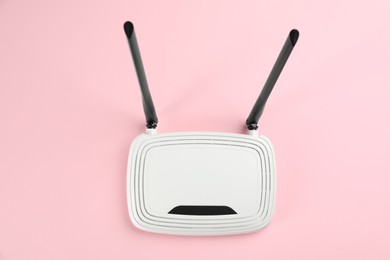 Photo of Modern Wi-Fi router on light pink background, top view