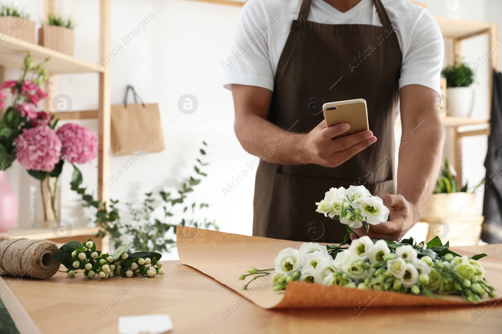 Photo of Florist taking picture of beautiful flowers in workshop, closeup