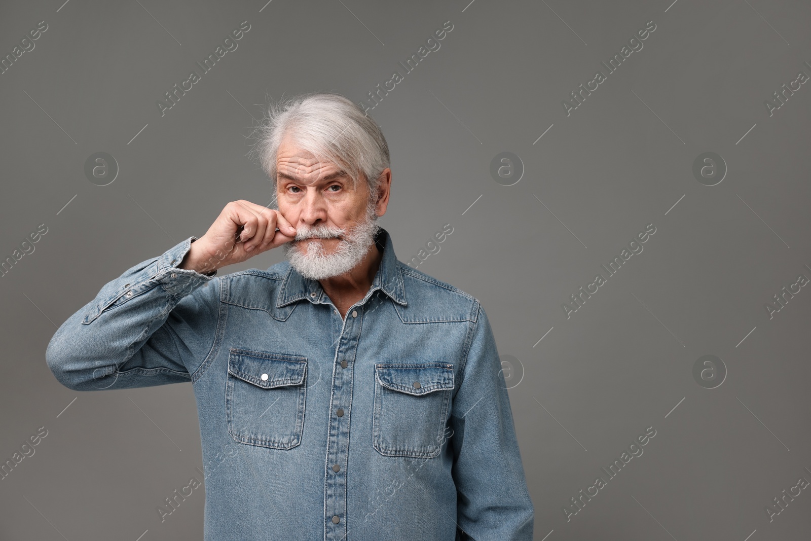 Photo of Senior man touching mustache on grey background, space for text