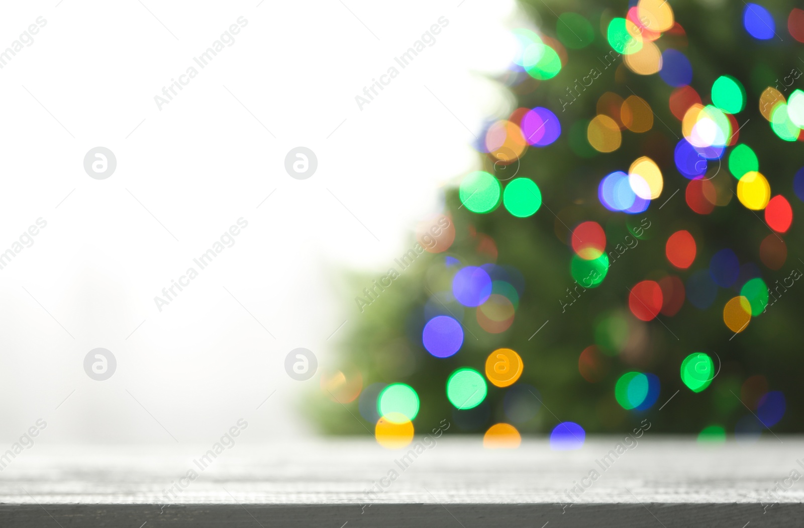 Photo of Empty table and blurred fir tree with colorful Christmas lights on background, bokeh effect. Space for design