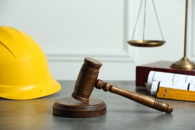 Construction and land law concepts. Judge gavel, scales of justice, construction helmet and drawings on wooden table