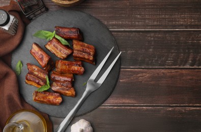Photo of Tasty roasted pork ribs served on wooden table, flat lay. Space for text