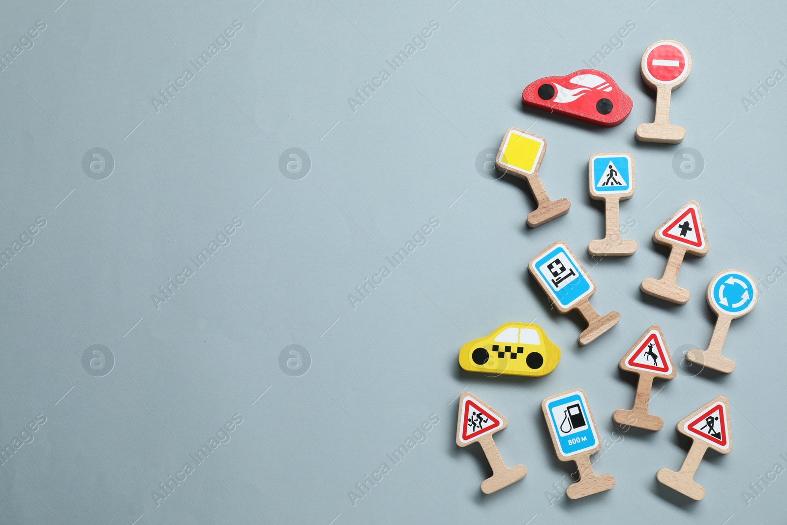 Photo of Set of wooden road signs and cars on light grey background, flat lay with space for text. Children's toy