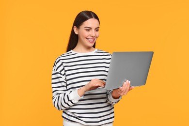 Photo of Happy woman using laptop on orange background