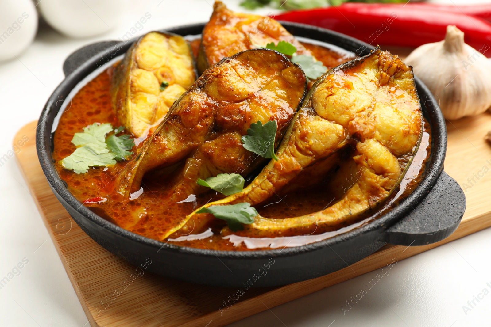 Photo of Tasty fish curry on white table, closeup. Indian cuisine