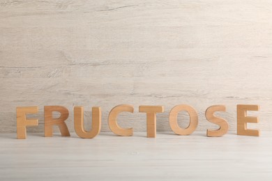 Word Fructose made of wooden letters on table