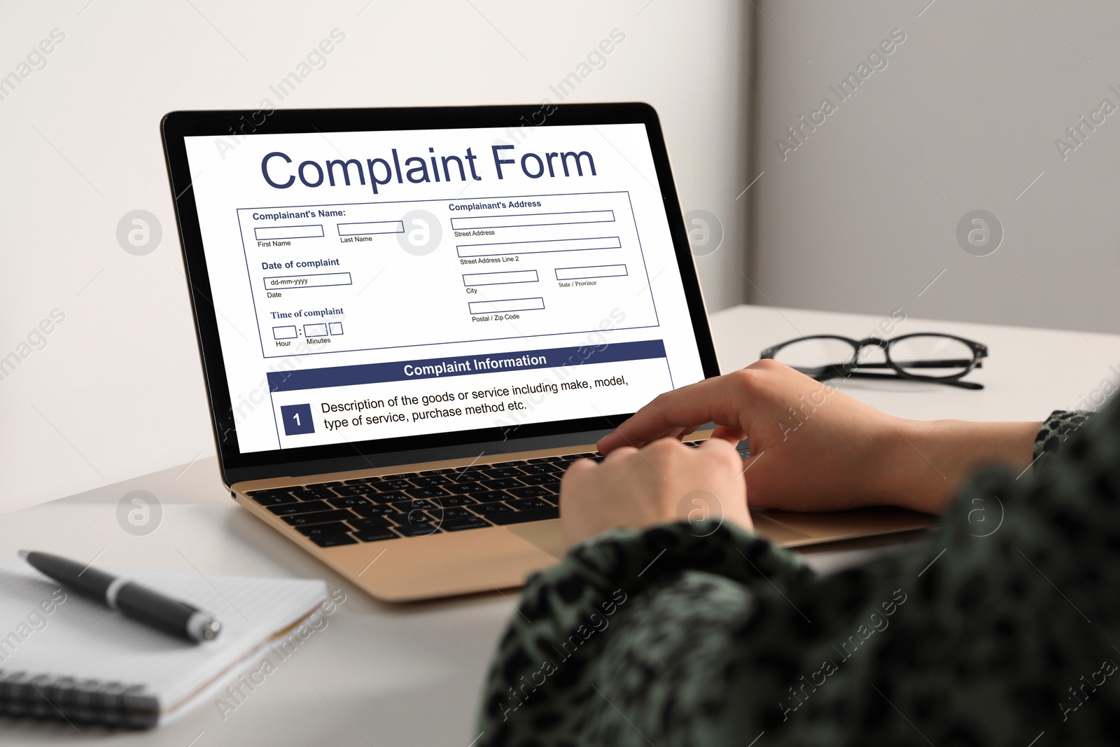 Image of Woman filling online complaint form via laptop at table, closeup