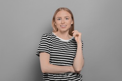 Photo of Portrait of beautiful young woman in striped t-shirt on grey background