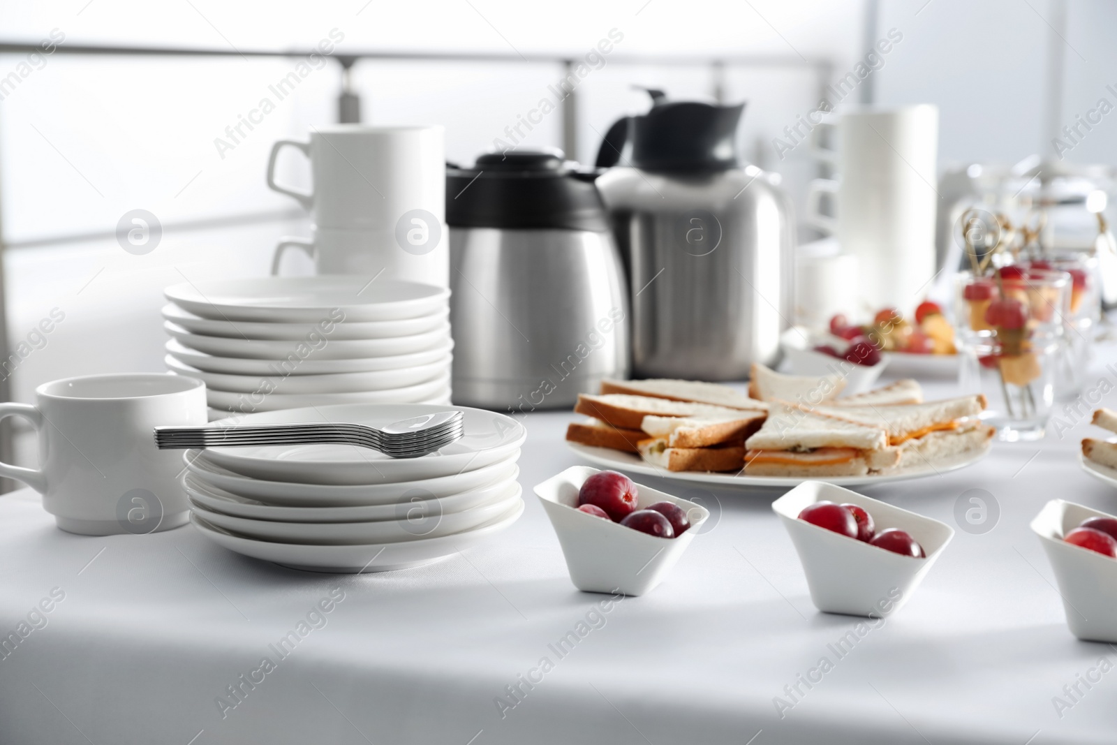 Photo of Table with different delicious snacks and dishware indoors. Coffee break