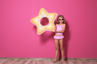 Photo of Cute little girl with bright star shaped inflatable ring near color wall