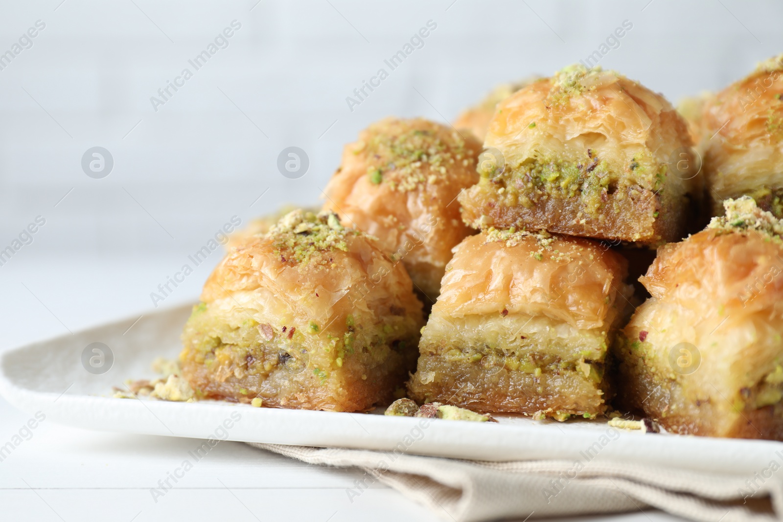 Photo of Delicious fresh baklava with chopped nuts on white table, closeup. Eastern sweets