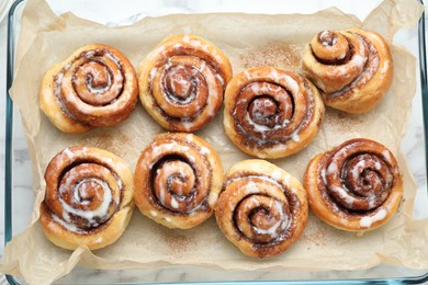 Photo of Baking dish with tasty cinnamon rolls on white marble table, top view