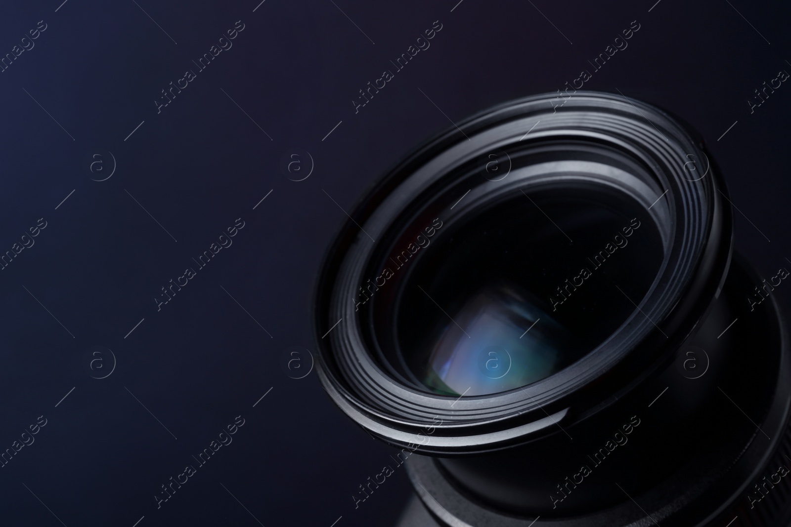 Photo of Lens of professional camera on dark blue background, closeup. Space for text