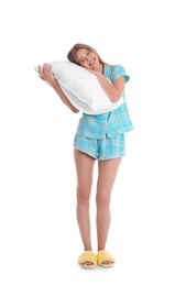 Young woman in pajamas embracing pillow on white background