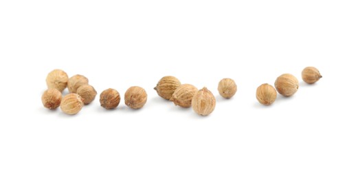 Scattered dried coriander seeds on white background