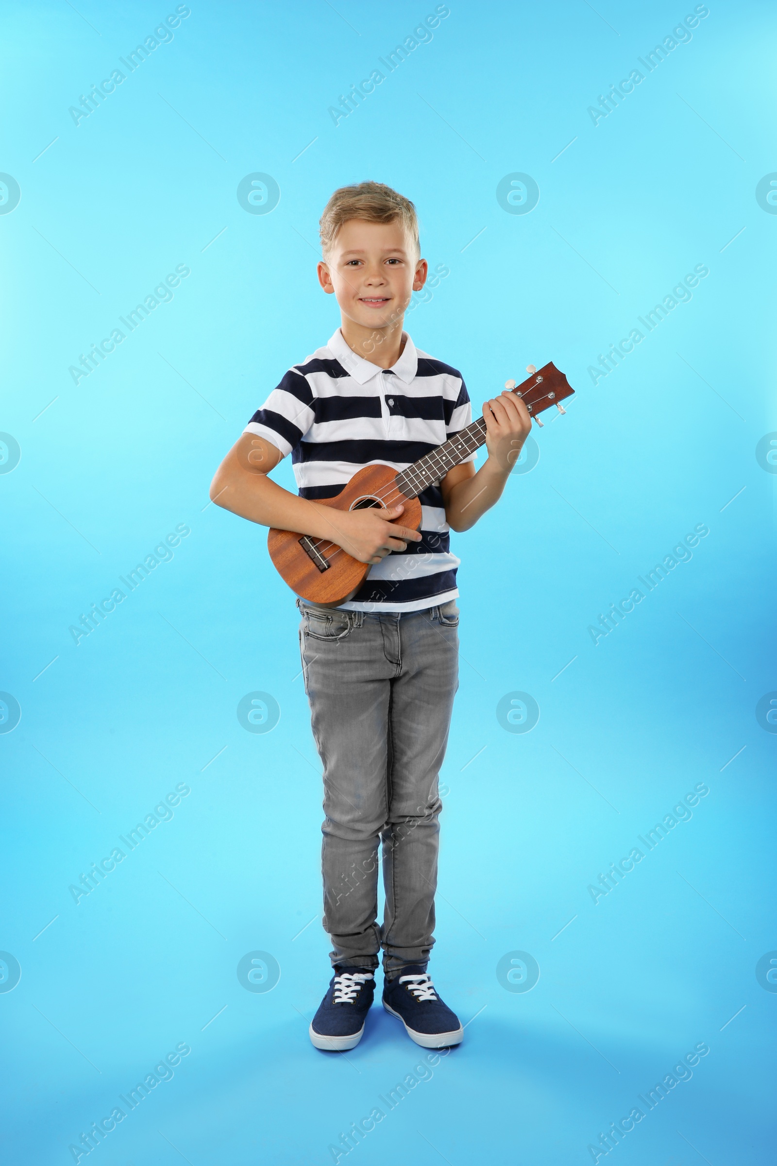 Photo of Little boy playing guitar on color background