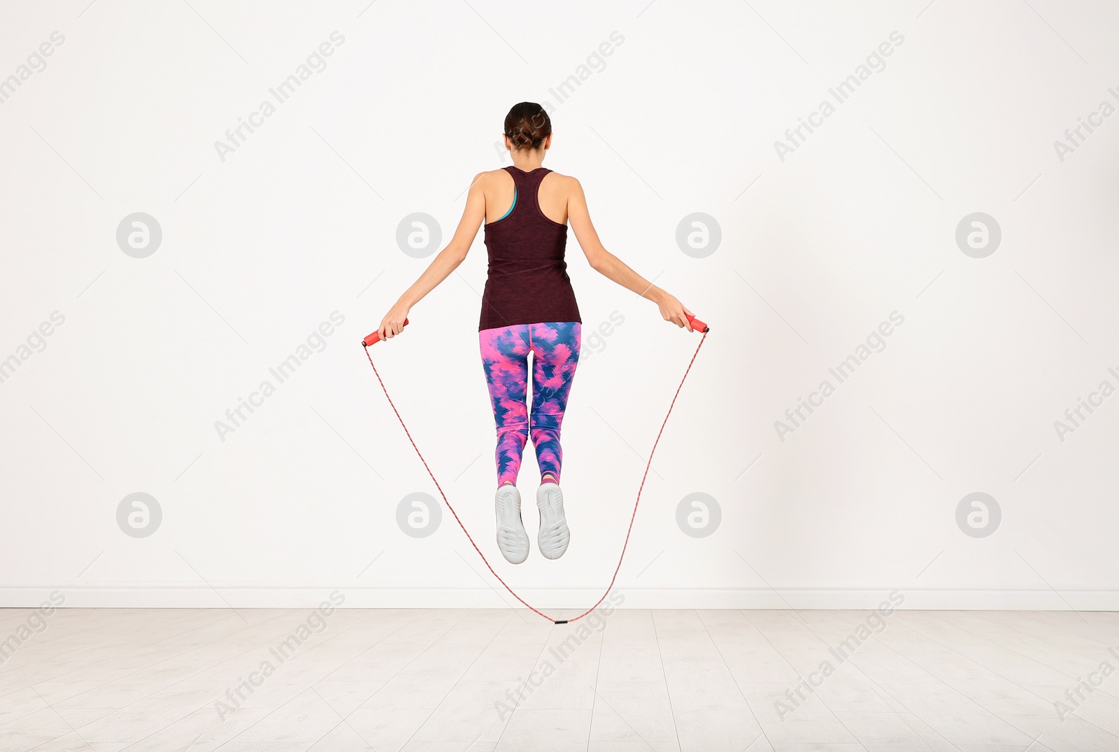 Photo of Sportive woman training with jump rope in light room