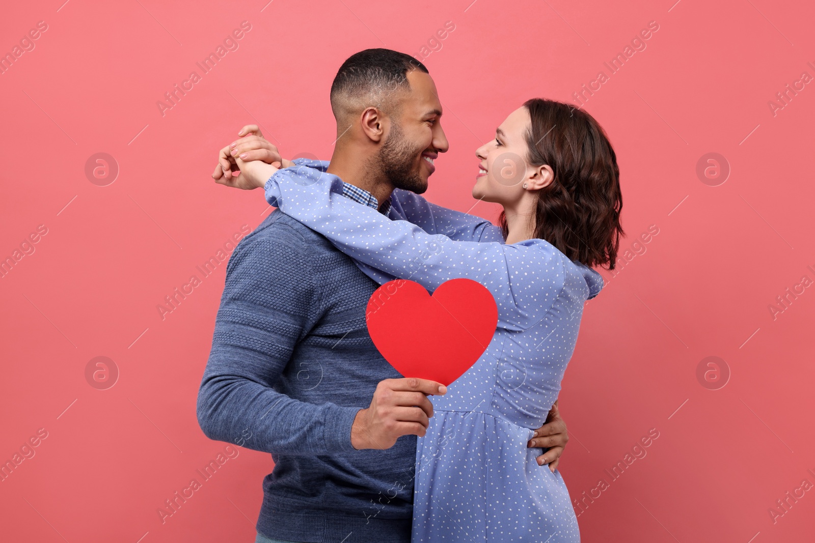 Photo of Lovely couple with paper heart on red background. Valentine's day celebration