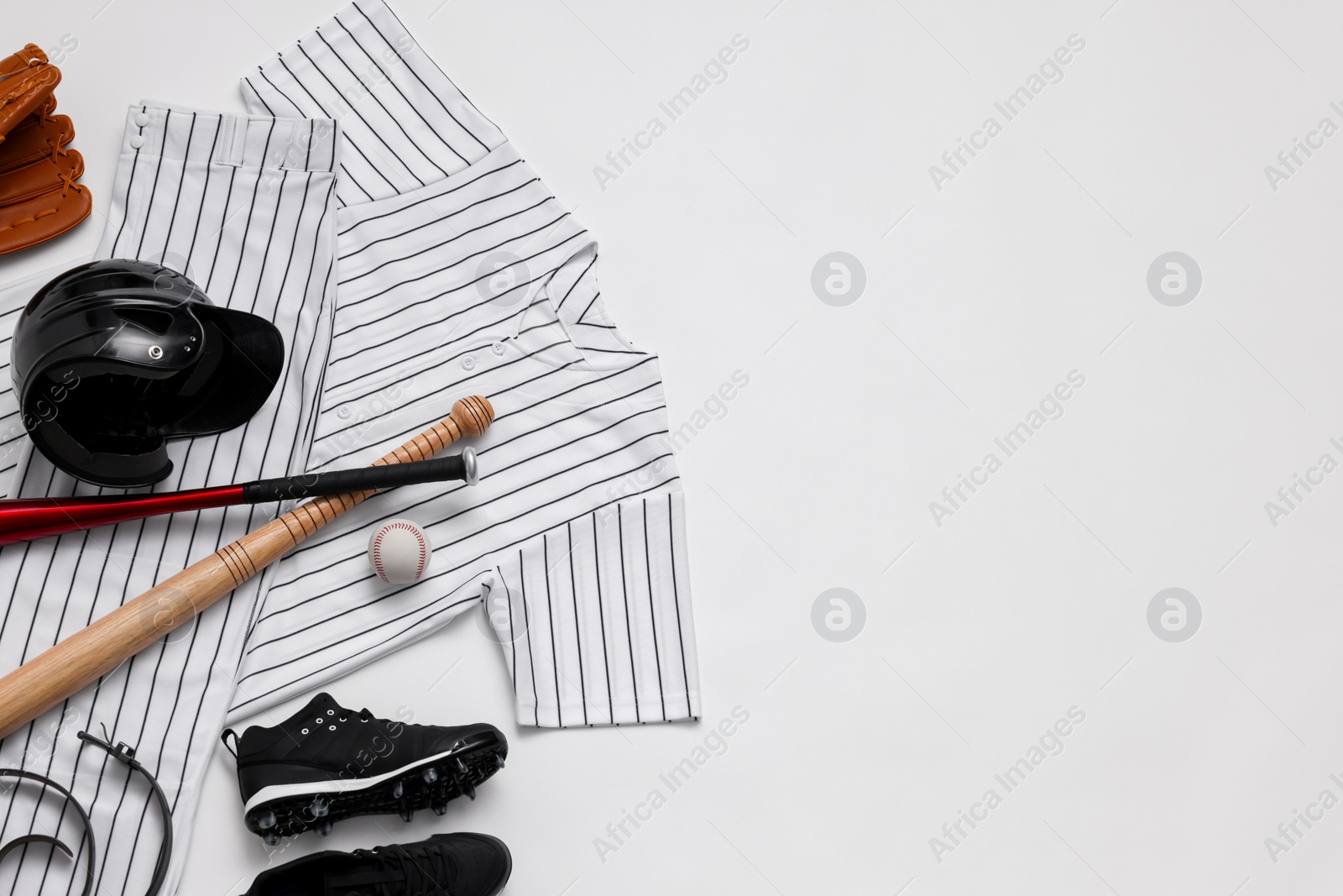 Photo of Baseball uniform and other sports equipment on white background, flat lay. Space for text