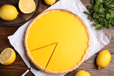 Delicious homemade lemon pie, fruits and mint on wooden table, flat lay