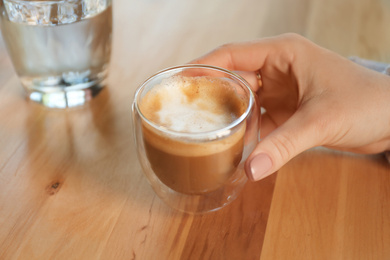 Woman with aromatic coffee at table in cafe, closeup