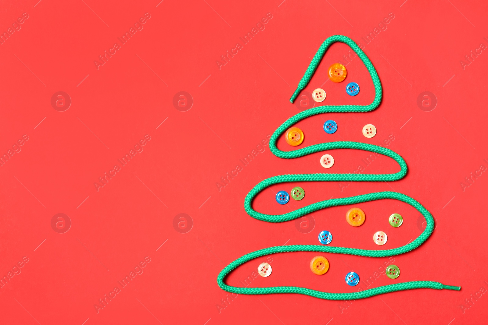 Photo of Christmas tree made of shoe lace and different buttons on red background, flat lay. Space for text