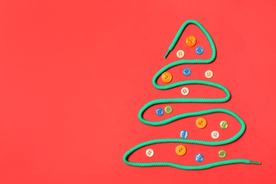Photo of Christmas tree made of shoe lace and different buttons on red background, flat lay. Space for text