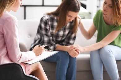 Photo of Young woman and her teenage daughter visiting child psychologist in office