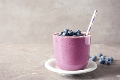 Photo of Glass with blueberry smoothie on grey table. Space for text