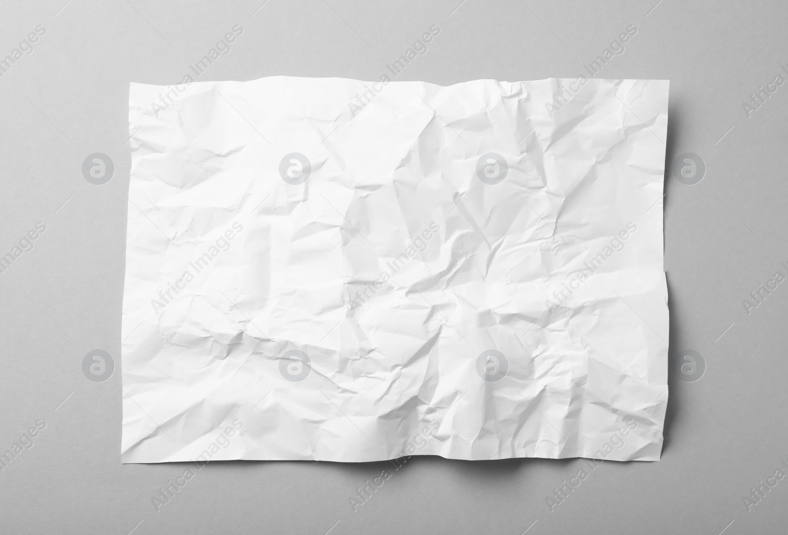 Photo of Sheet of white crumpled paper on grey background, top view