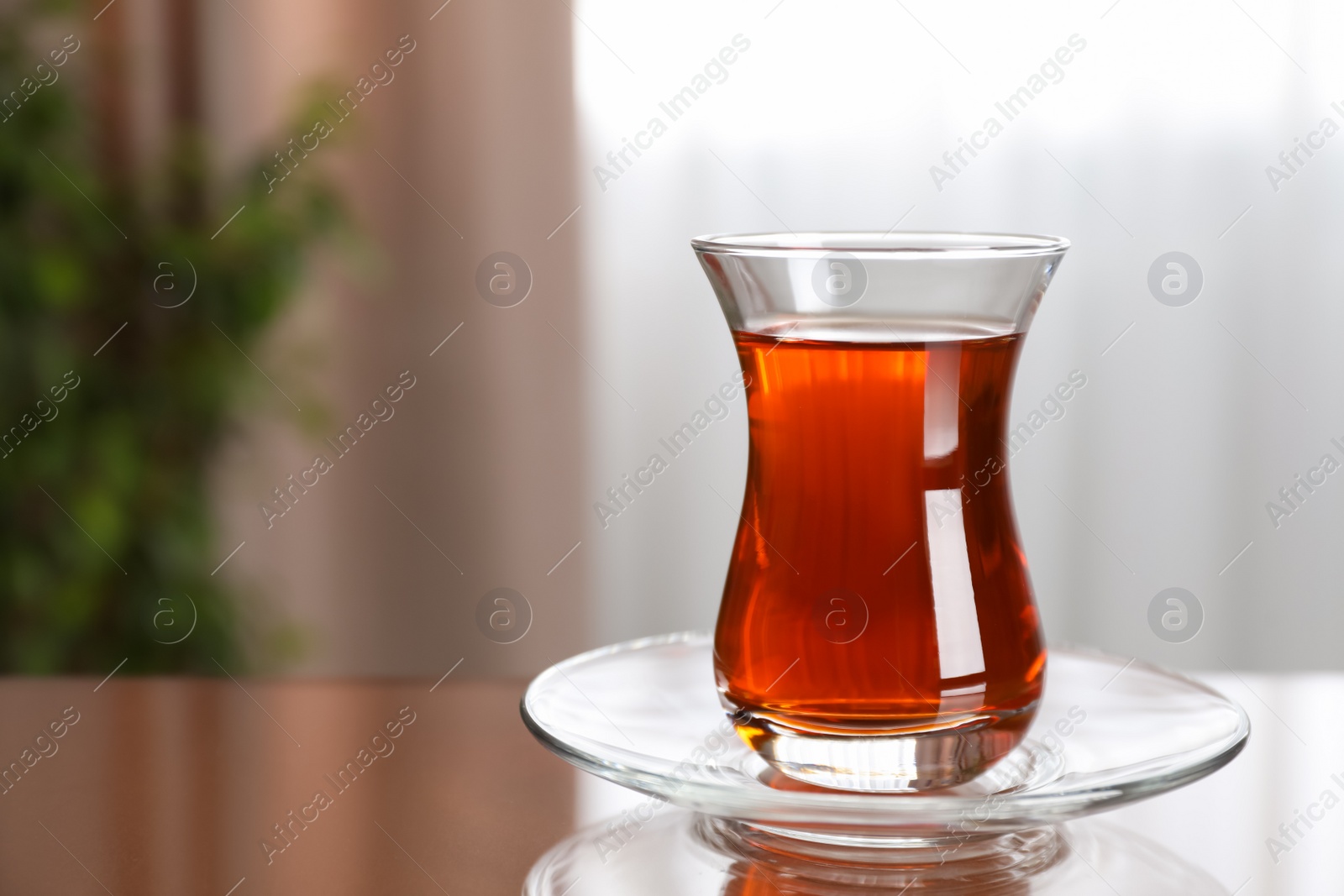 Photo of Glass with tasty Turkish tea on brown table indoors, space for text