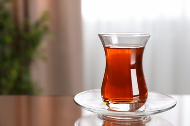 Photo of Glass with tasty Turkish tea on brown table indoors, space for text