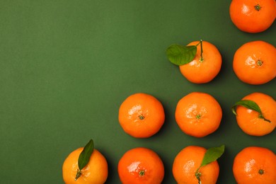 Delicious tangerines and leaves on green background, flat lay. Space for text