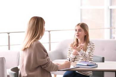 Photo of Young female psychologist working with teenage girl in office