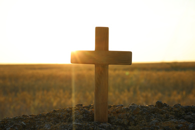 Photo of Wooden Christian cross outdoors at sunrise. Religion concept