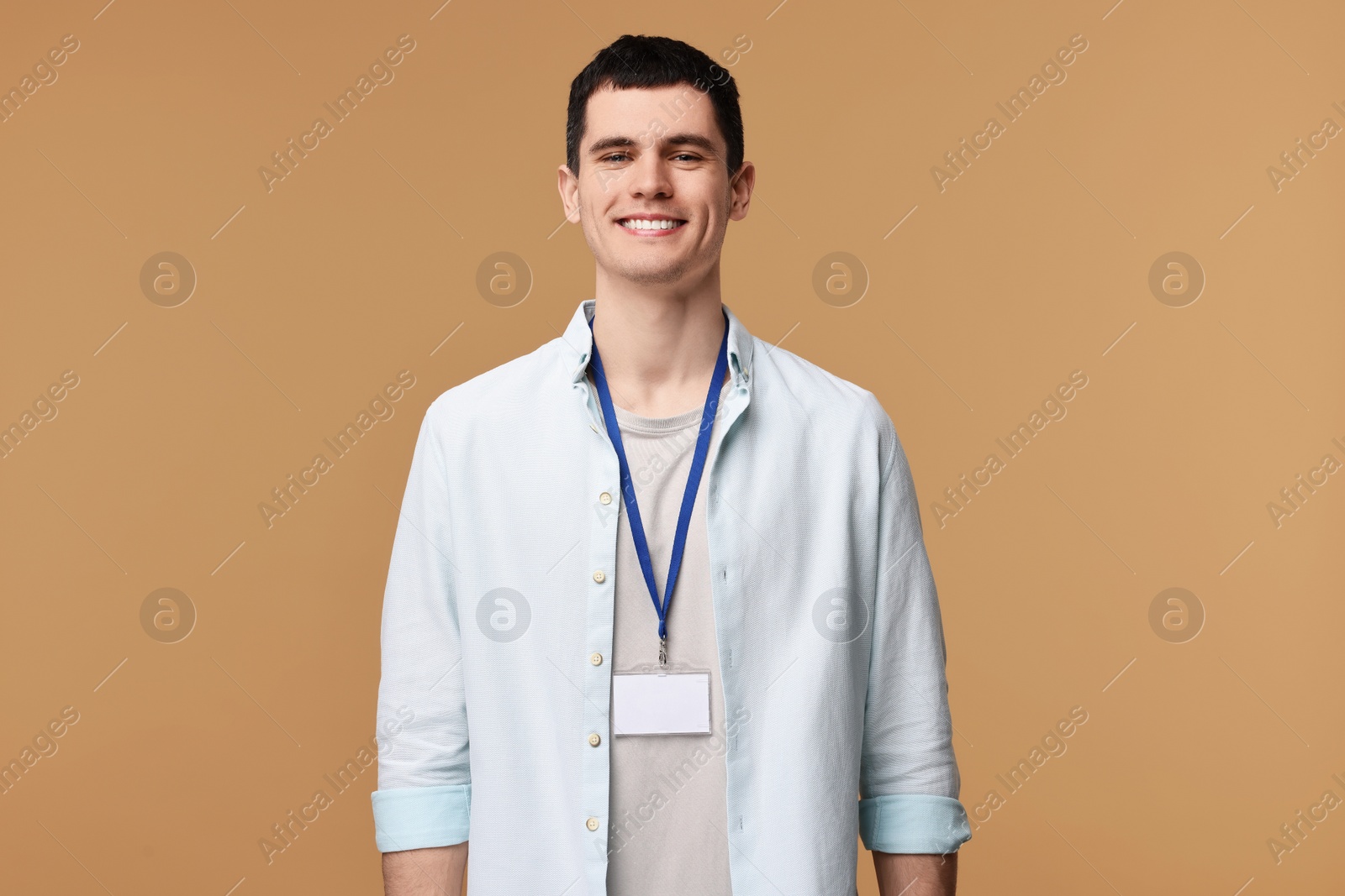 Photo of Smiling man with empty badge on beige background