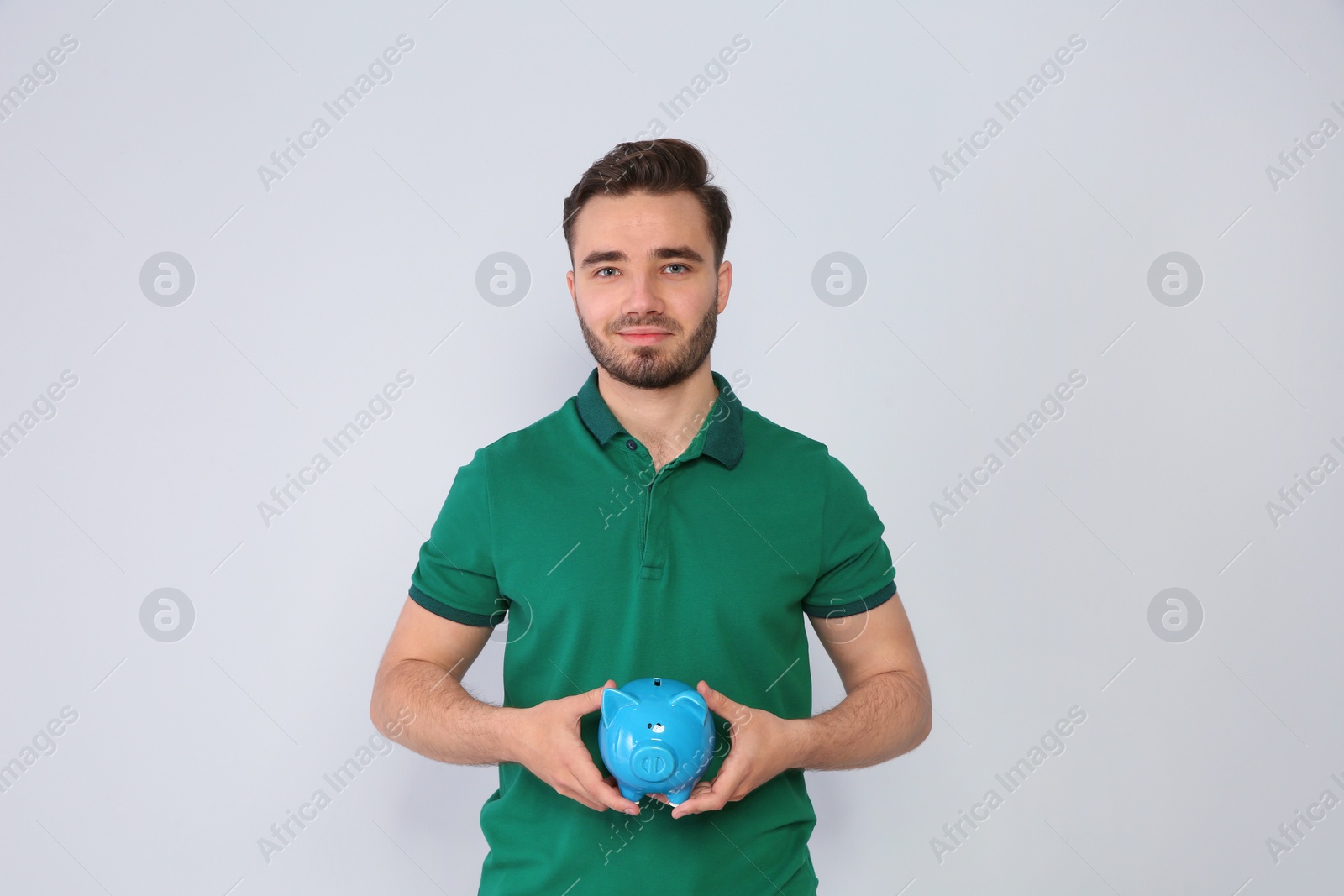 Photo of Young man with piggy bank on light background