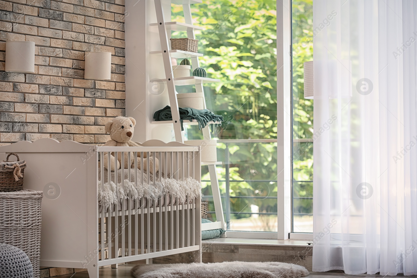 Photo of Baby room interior with crib near brick wall