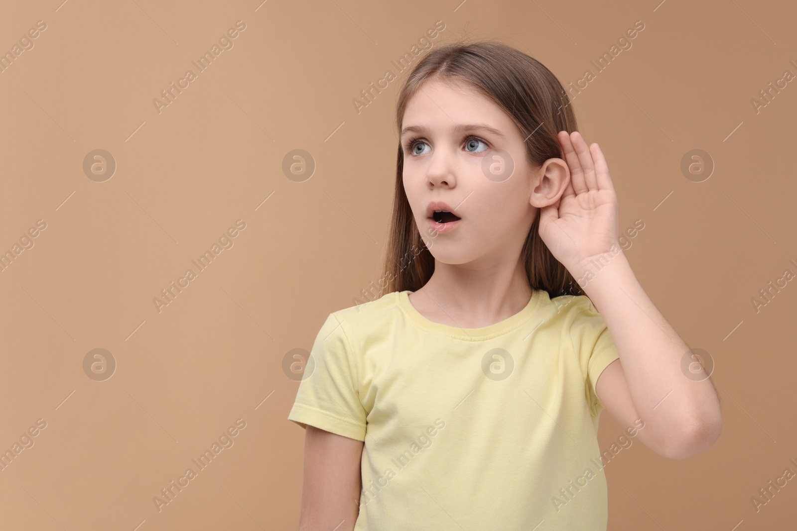 Photo of Little girl with hearing problem on pale brown background, space for text