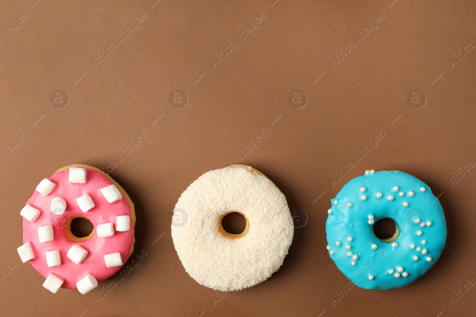 Photo of Sweet tasty glazed donuts on brown background, flat lay. Space for text