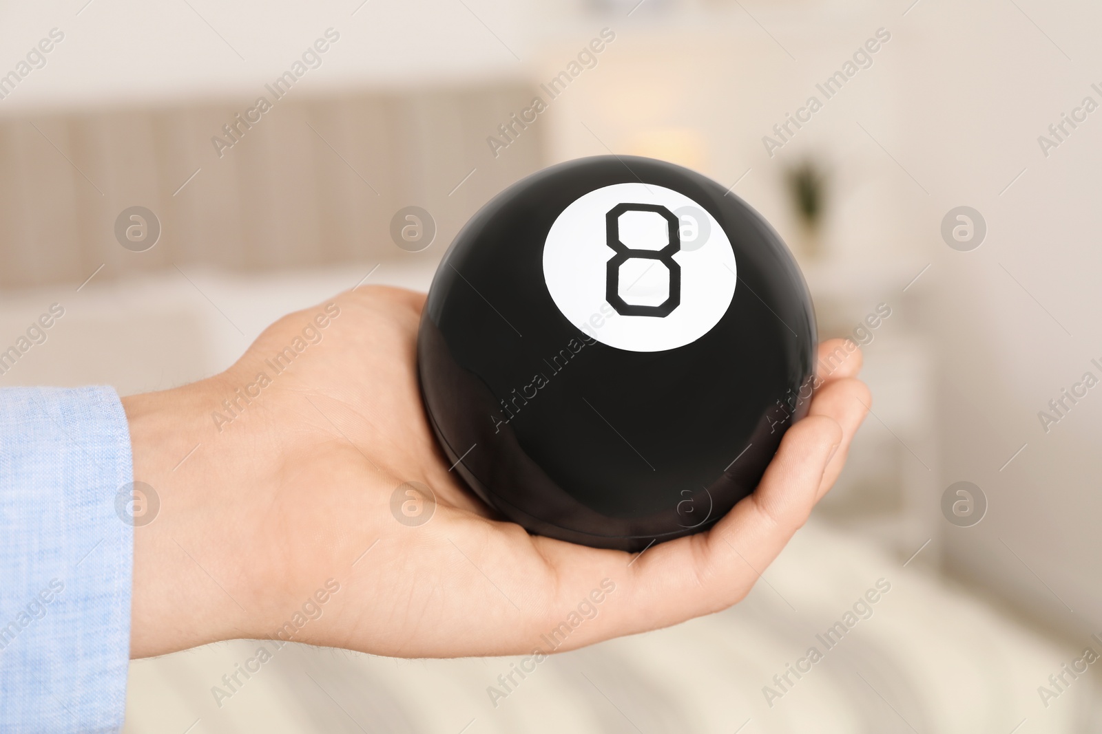 Photo of Man holding magic eight ball indoors, closeup