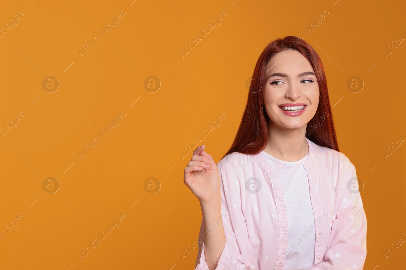 Photo of Beautiful woman with red dyed hair on orange background, space for text