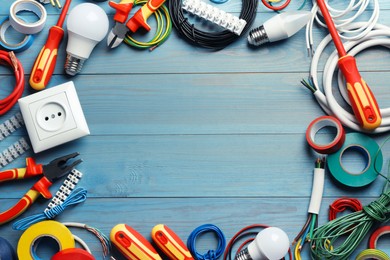 Frame of electrician's tools and accessories on light blue wooden table, flat lay. Space for text