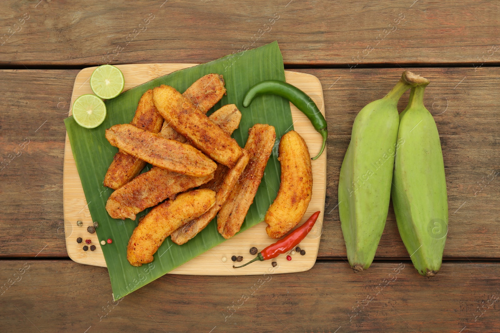 Photo of Delicious fried bananas, fresh fruits and different peppers on wooden table, flat lay