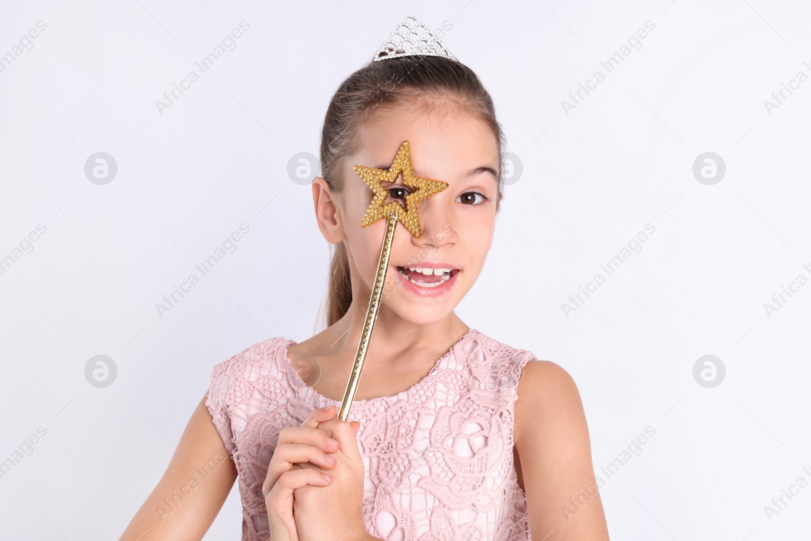 Photo of Cute girl in diadem with magic wand on white background. Little princess