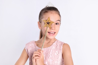 Cute girl in diadem with magic wand on white background. Little princess