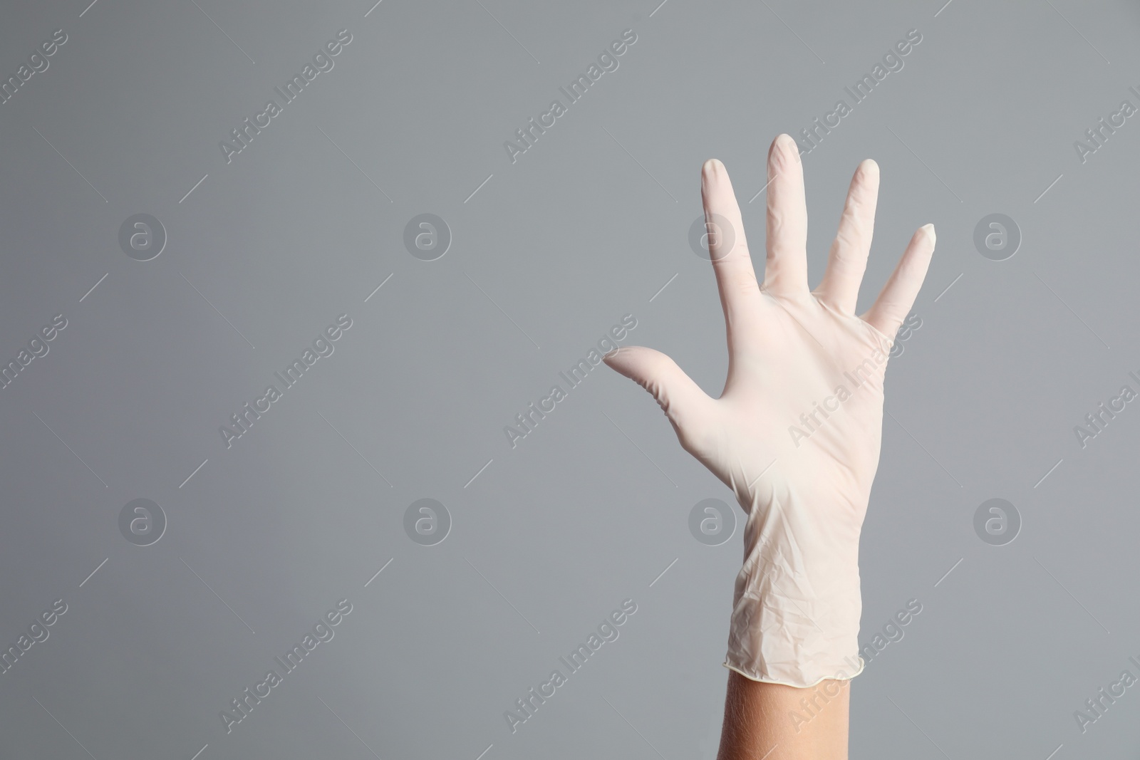 Photo of Doctor wearing medical gloves on grey background, closeup. Space for text