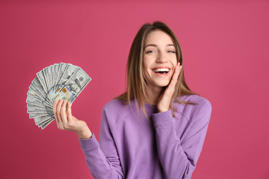 Happy young woman with cash money on pink background